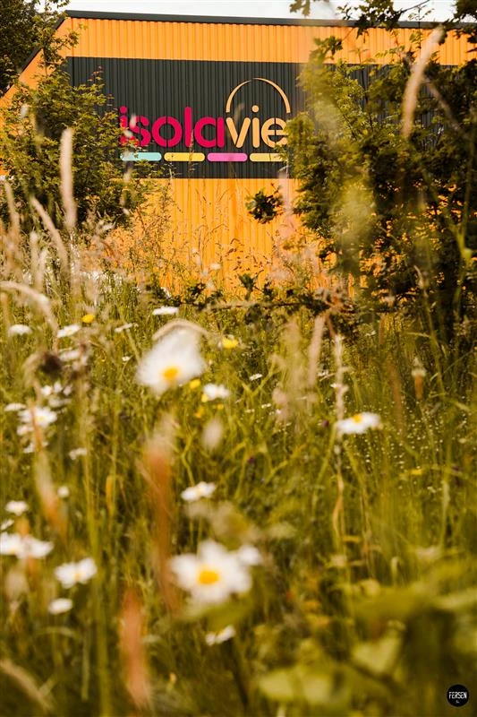 Le bâtiment IsolaVie au milieu des fleurs sauvages